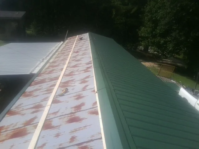 Old rusted panels beside newly installed green metal roofing — Wind Damage Roof Repair by Roofing Brothers in Orrstown