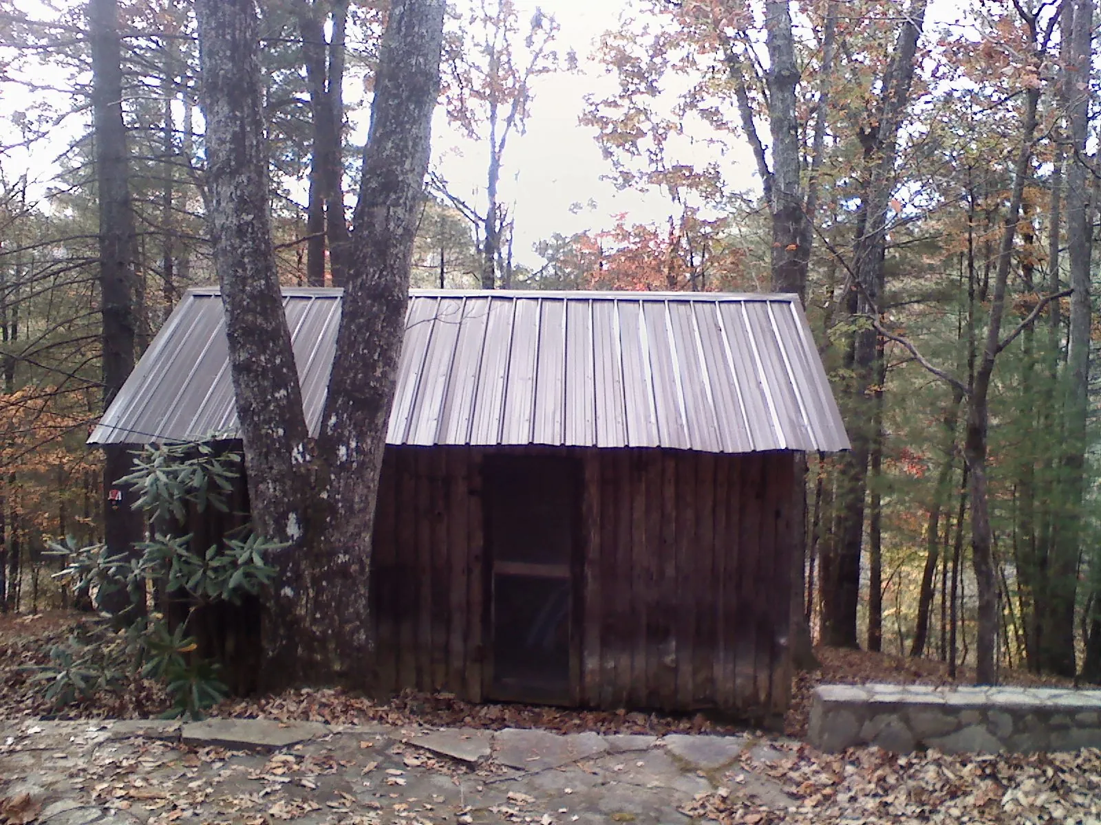 New metal gable roof on a small log shed among the trees in Orrstown