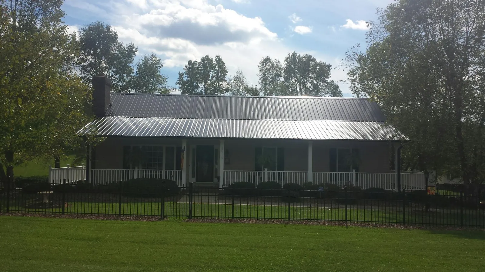 Gray metal roof on a brick ranch with a full width front porch — Gutter Guard Installation work by our crew in Orrstown