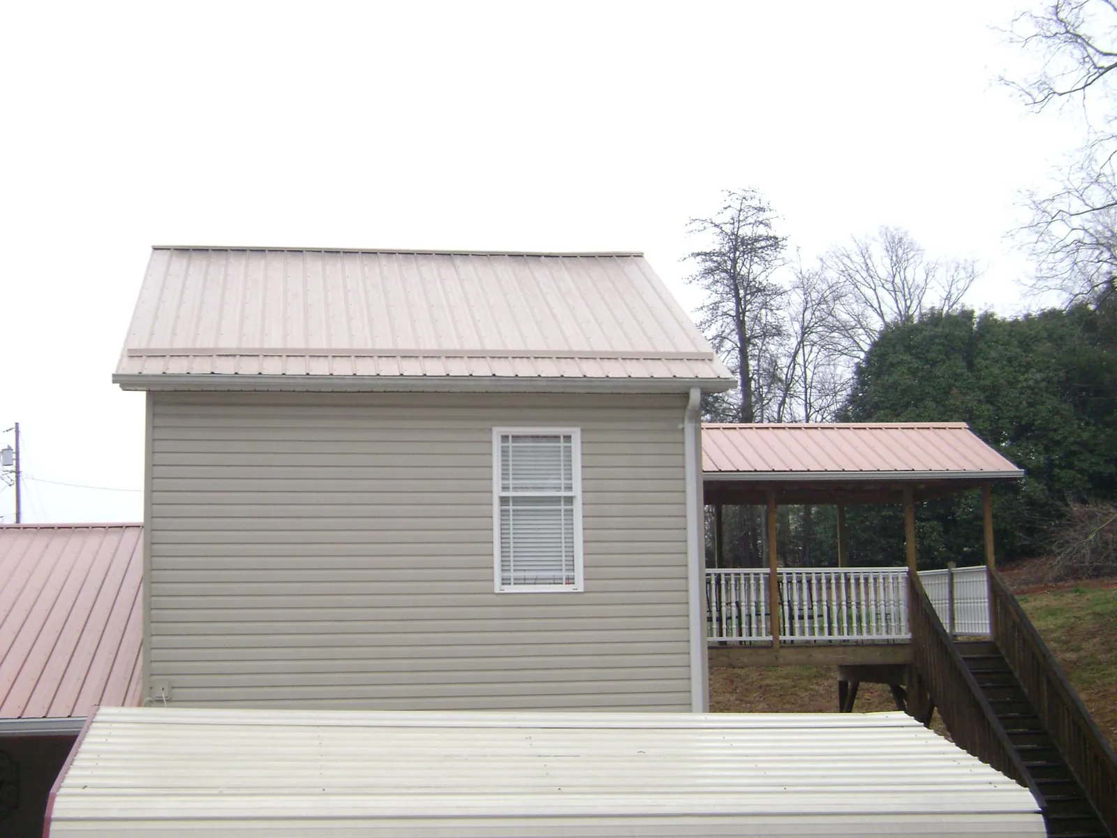 Tan metal roofs on a two story addition and attached porch, from a Roof Replacement job in Orrstown