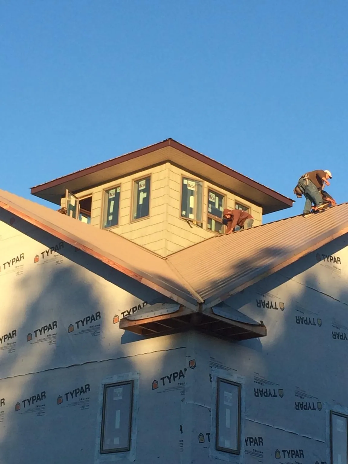 Roofers working around a rooftop cupola on a new metal roof at sunset — Roof Waterproofing in Orrstown by Roofing Brothers